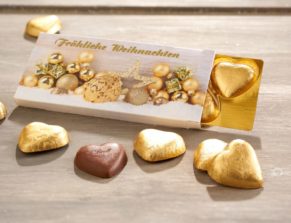 Der besondere Weihnachtsgruß. In der Präsent-Schachtel befinden sich fünf goldene Vollmilch-Schokoladen Herzen der Marke Lindt. Insgesamt ca. 25 g Schokolade, Maße: ca. B11,5 x T1 x H5,5 cm. Zutaten: Alpenvollmilch-Schokolade (Kakao: 30% mindestens): Zucker, Kakaobutter, VOLLMILCHPULVER, Kakaomasse, MILCHZUCKER, MAGERMILCHPULVER, Emulgator (SOJALECITHIN), GERSTENMALZEXTRAKT, BUTTERREINFETT, Aroma Vanillin. Allergiehinweis: Kann Spuren von Haselnüssen und Mandeln enthalten<br>