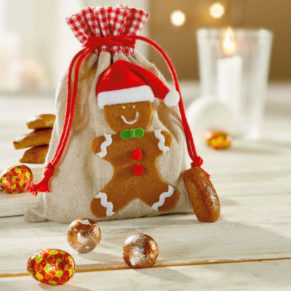 Zugbeutel mit Lebkuchenmann-Motiv gefüllt mit 60g Süßwaren. Gefüllt mit Mini Kräuter Printinchen, Vollmilch-Schokokugeln mit Kakaocreme-Füllung, Zapfen mit Pralinenfüllung, der Zugbeutel in Leinenstruktur mit einem Lebkuchenmann mit Weihnachtsmütze (